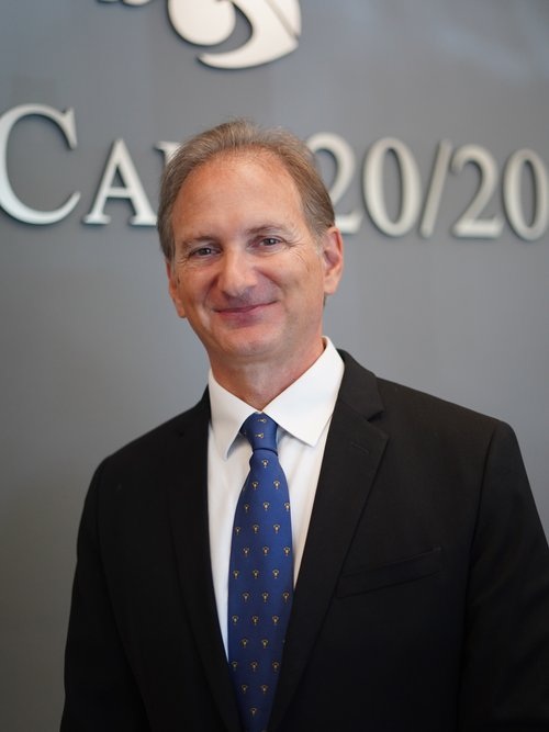 Dr. Neil Notaroberto, Founder and Retinal Specialist - EyeCare 20/20 Retina & Vision Center Dr. Neil Notaroberto, a retinal specialist and founder of EyeCare 20/20 Retina & Vision Center, stands in front of a clinic sign wearing a black suit, white shirt, and blue patterned tie, smiling confidently. - EyeCare 20/20 Retina & Vision Center